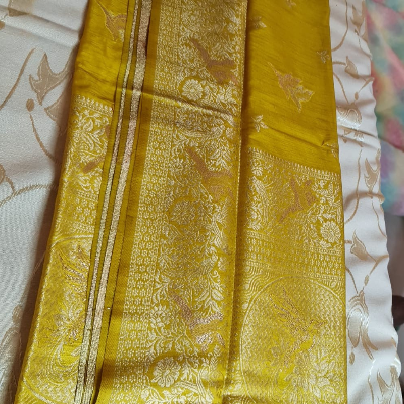 Yellow Benarasi saree with intricate gold zari detailing with tassels